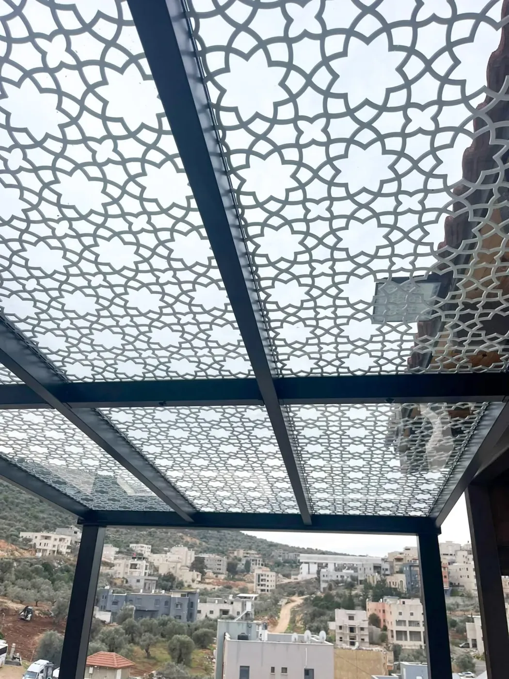 Glass pergola roof with laser-cut Islamic-pattern shading over a terrace — BlueCrest, Egypt